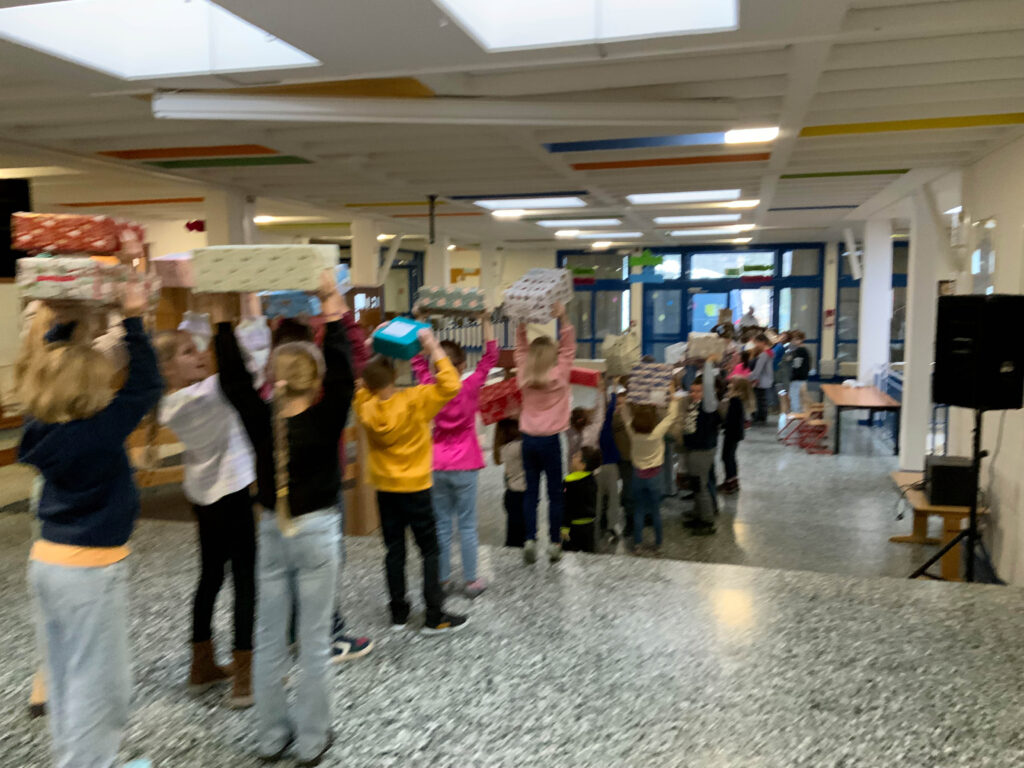 Das Bild zeigt Grundschüler, die ihre Geschenkpakete für rumänische Kinder zum Transporter bringen.